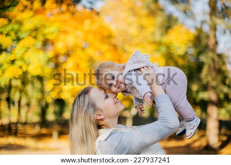 Young mother kissing her baby daughter in autumn park