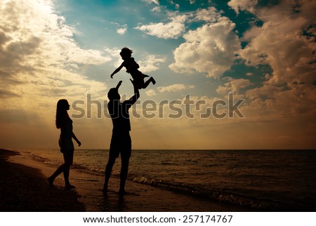 happy family silhouettes on beach at sunset
