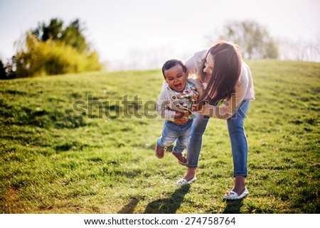 Happy interracial family. Caucasian mother and her african american son having fun in park