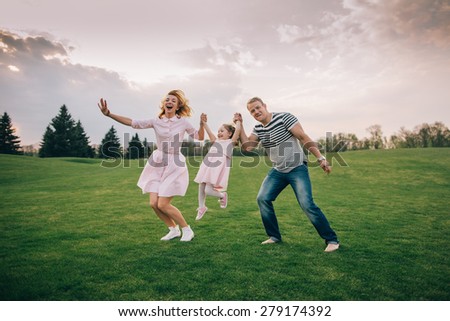 Happy to be a family. Happy family of three jumping and laughing outdoors