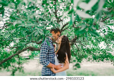 Tilt-shift photo of beautiful young couple kissing under the tree