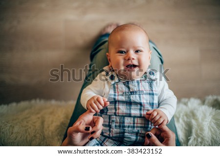 Mother holding her smiling newborn son in hands