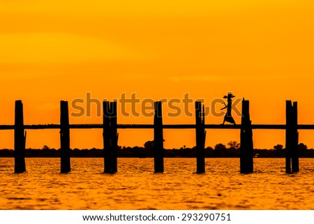 Silhouetted person on U Bein Bridge at sunset, Amarapura, Mandalay region, Myanmar