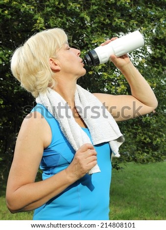 A Older woman with drinking bottle and towel doing sports