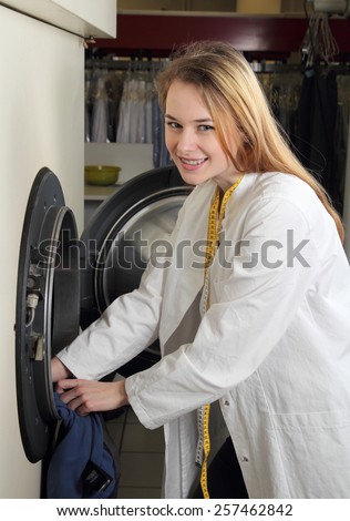 An Employee of dry cleaning loads a professional washing machine
