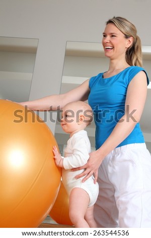 A Baby standing at Physiotherapy beside a Fitness Ball