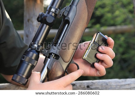 A Hunter loading his hunting rifle gun with magazine
