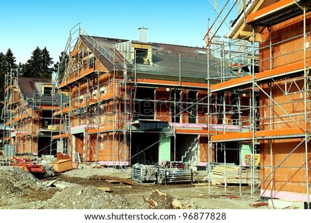 Development construction site with 3 houses in scaffolding