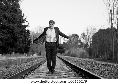 Young attractive man with suit smiling in the railway tracks