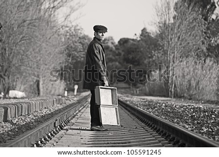 Young man with hat and old suitcase in rail way