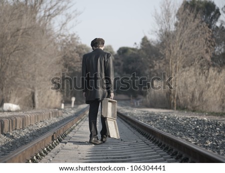 Young man with hat and old suitcase in rail way