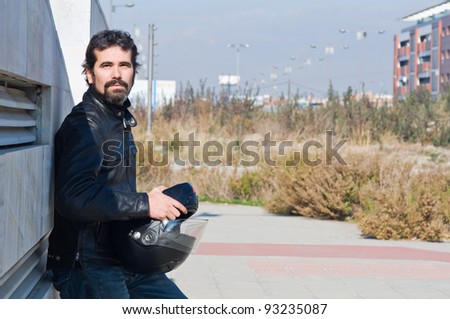 Portrait of young handsome man with leather jacket and motorcycle helmet