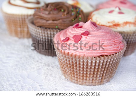 Close up set of colorful cupcakes on retro white tablecloth background. Chocolate Cupcake, strawberry pink, bright white vanilla. Cafe, restaurant, sweets, cakes.
