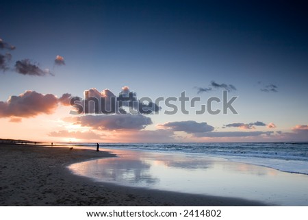 people walking on the beach with reflections on thin layer of water