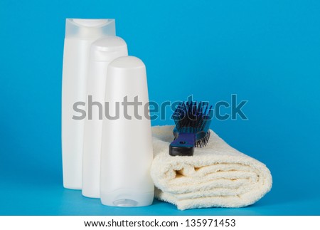 Set of cosmetics and hairbrush on a towel on a blue background