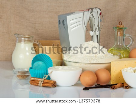 Mixer, cake pan, spices, eggs and dairy products for dough, against a canvas