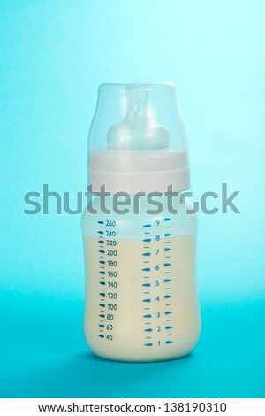 Children\'s small bottle with milk and a pacifier on a blue background