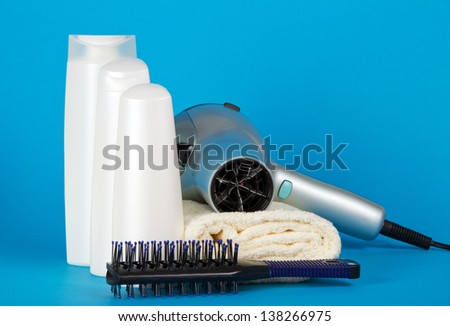 Set of cosmetics, the hair dryer and hairbrush on a towel on a blue background
