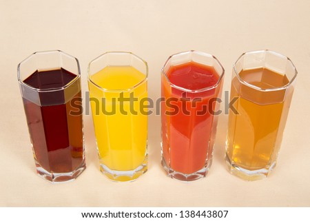 Glasses with different juice on a beige cloth
