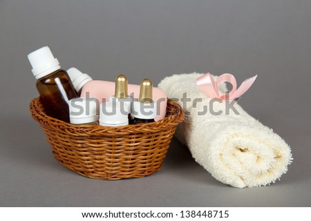 Hotel cosmetics kit and terry towel in basket, on a grey background