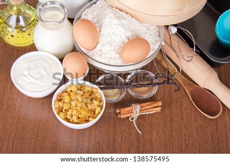 Raisin, sesame, sticks of cinnamon and vanilla pods, a flour and eggs on a table
