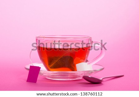 Cup with a tea bag on a saucer on a pink background