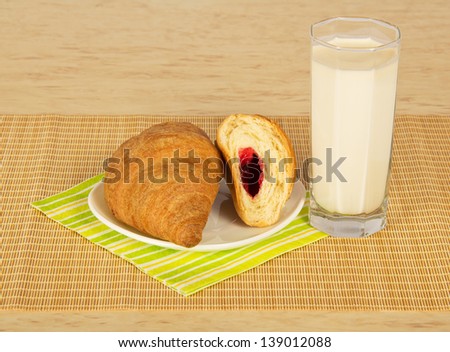 Croissants, milk, striped napkin on a beige bamboo cloth