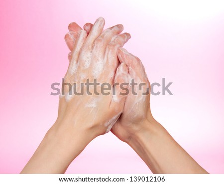 Foam of soap and female hands, on a pink background