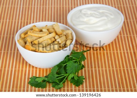 Bowl with sour cream, a bowl with toasts and parsley,on a beige bamboo cloth