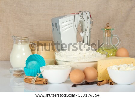 The cake pan, a mixer, a sieve and a  products for dough, on a beige canvas