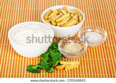 Sour cream, croutons, salt and parsley on a beige bamboo cloth