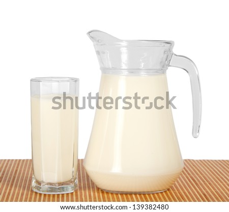 Jug and glass with milk on the bamboo cloth, isolated on white.