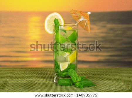 Mojito, is decorated with an umbrella and a slice of lemon and spearmint on a green bamboo cloth