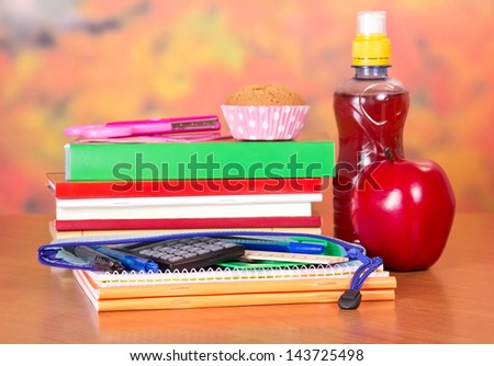 A set of school accessories, bottle with drink, cake and apple, on a table