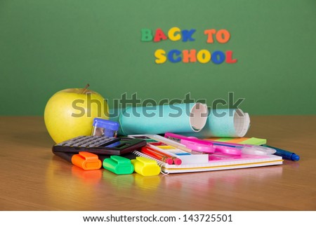 School set for the letter and drawing, the calculator and an apple on a table