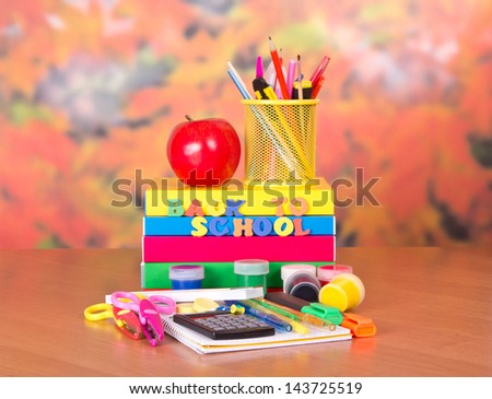 Books, a set of accessories to drawing and the letter and apple on a table