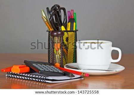 Blank sheets for notes, a set of office supply in a support and a cup of coffee on a table