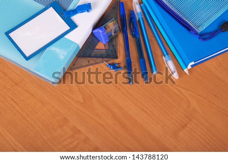 The book, the folder, pencil-case, handles, a pencil and an empty badge on a table