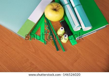 The book, the folder, exercise books, a set of office tools and apple on a table