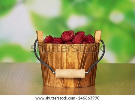 Wooden bucket of ripe fragrant raspberries on a table