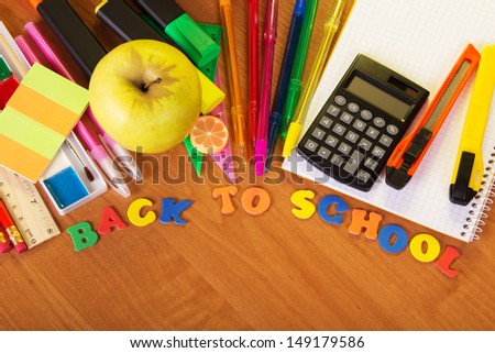 Blank exercise book sheets, handles, markers, the calculator a cutter and apple on a table