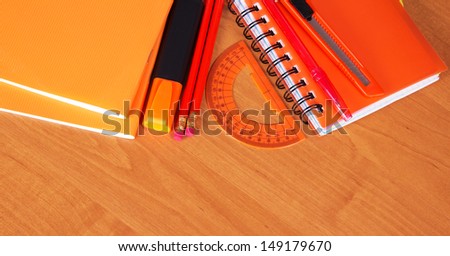 Exercise books, the notepad, pen, pencil, marker, cutter and protractor on a table