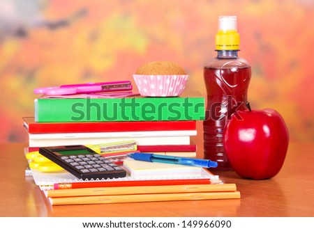 A set of school accessories, bottle with drink, cake and apple, on a table