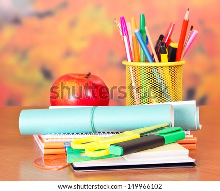Exercise books, scissors, writing materials, and apple, on a table