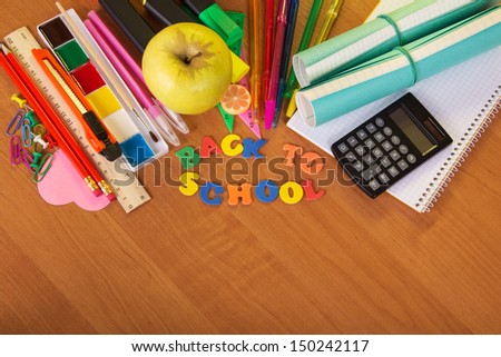 A roll of exercise books, a set for the letter and drawing, a calculator and apple on a table