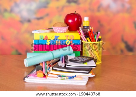 A set of school accessories, a cake, apple and drink on a table