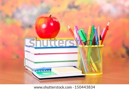 Books, apple, pencils and handles in a support and empty cards, on a table