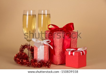 Boxes with New Year\'s gifts, wine glasses with champagne, tinsel on a beige background