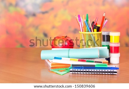 Notepad, writing materials and paints, on a table