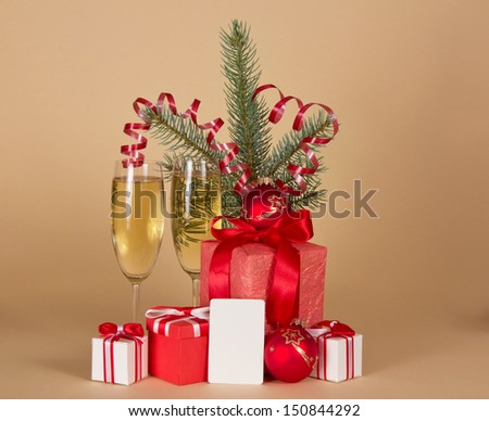 Christmas gifts, toys, tinsel, fir-tree branch, champagne and empty card, on a beige background